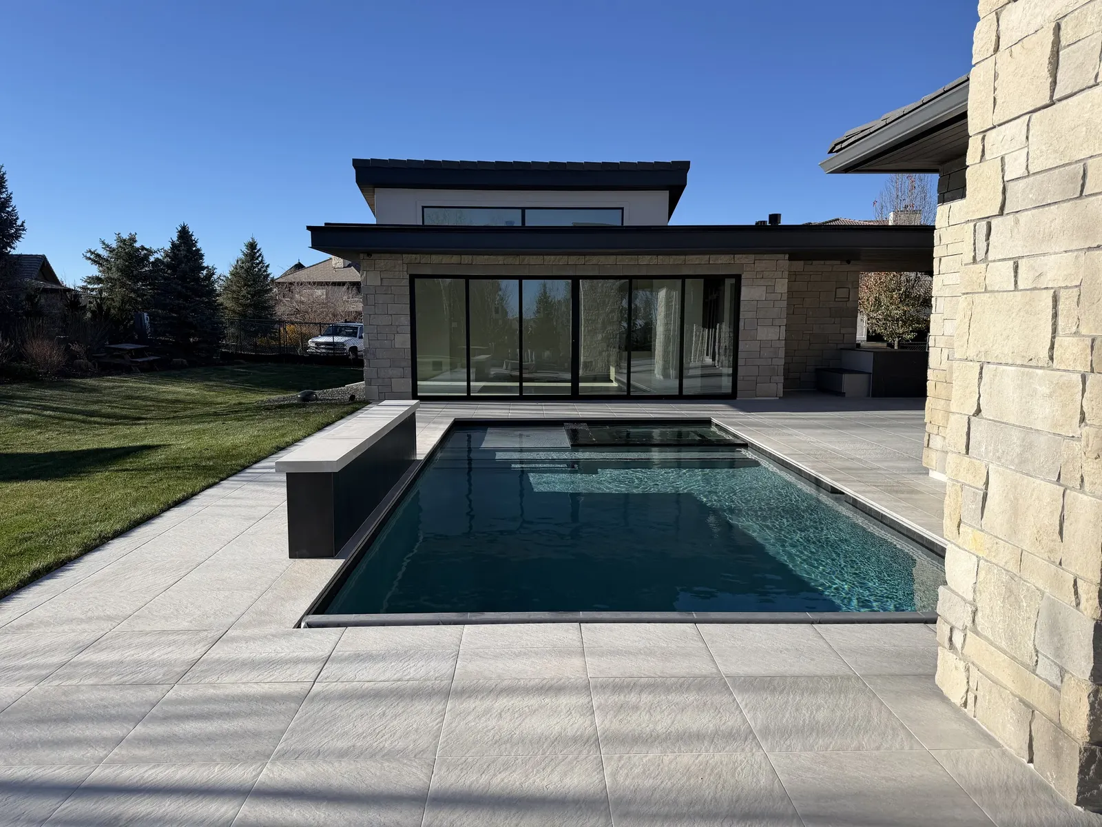 Stone terrace and rectilinear pool beside a contemporary house