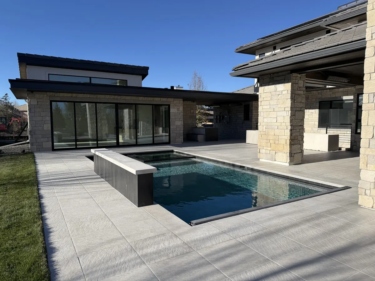 Dark-bottom pool reflecting a contemporary stone house