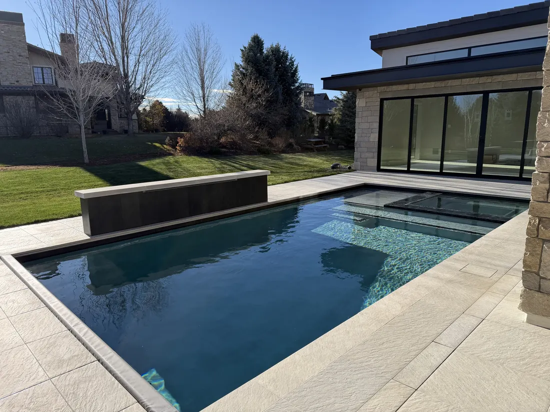 Pool reflecting the house with mature evergreens beyond