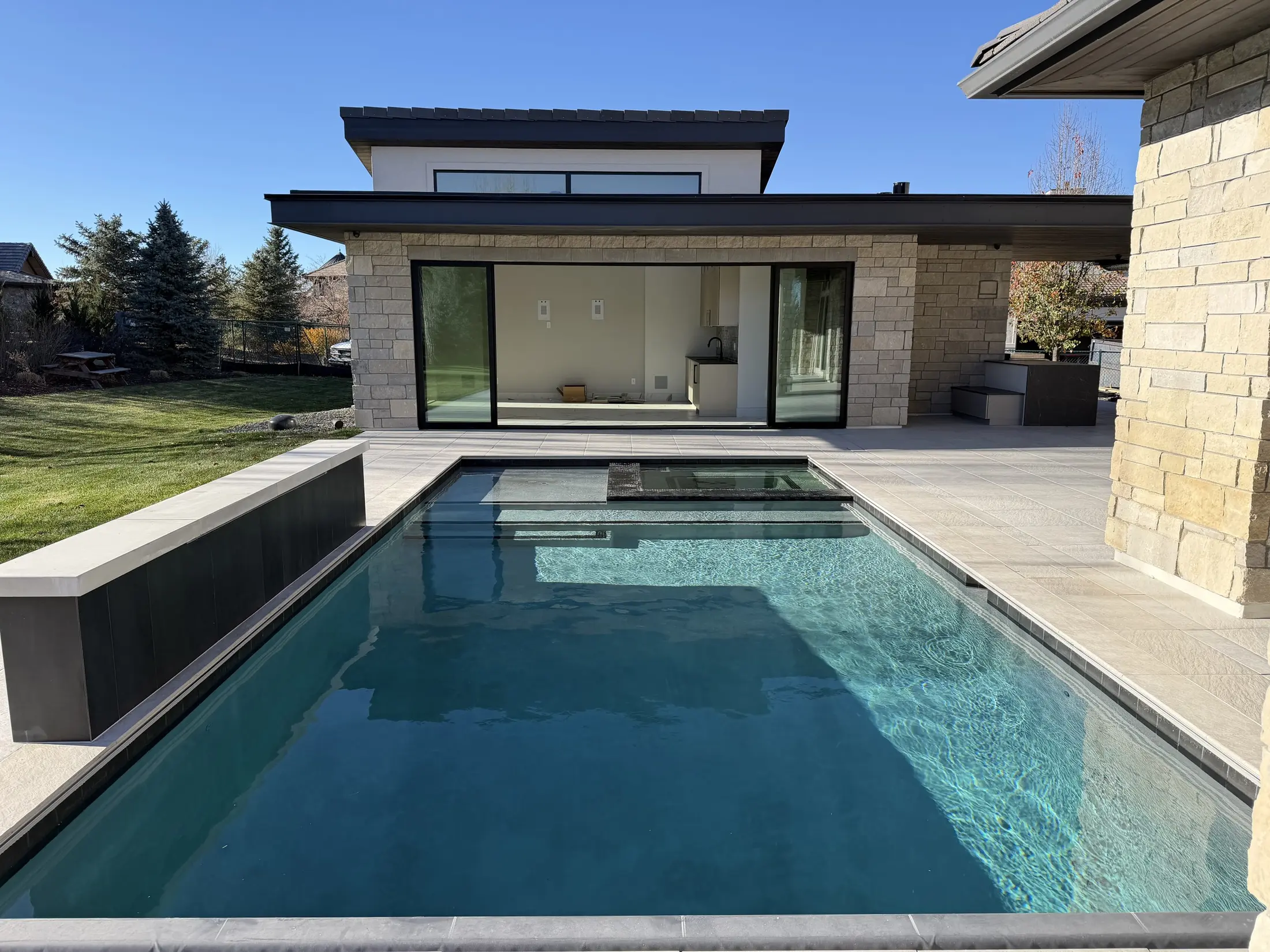 Dark-bottom pool reflecting a contemporary stone residence