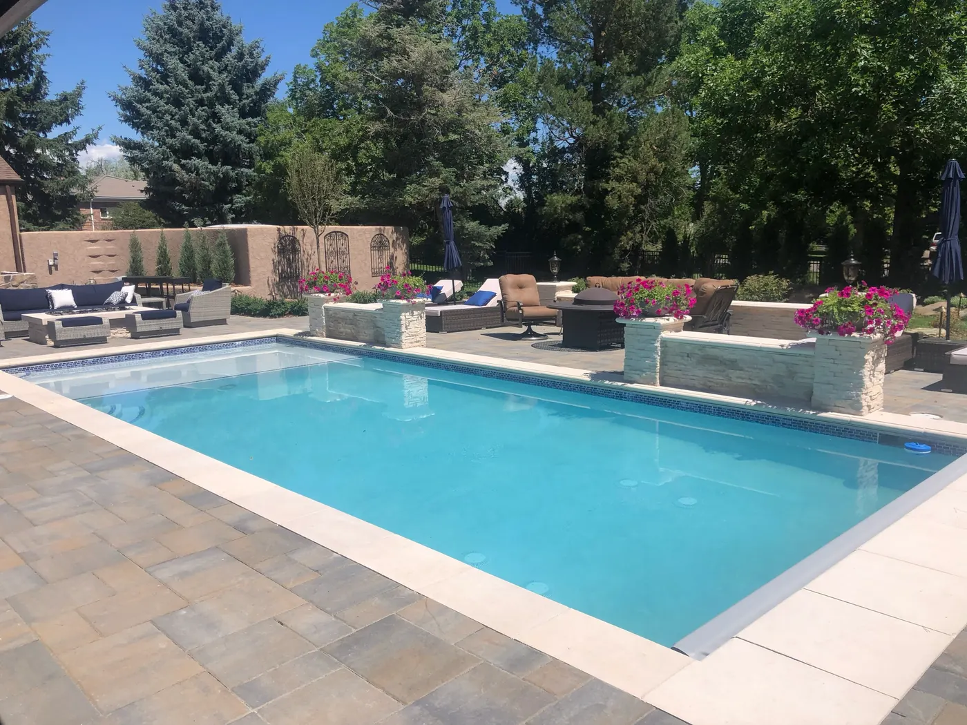 Rectilinear pool and stone coping with terrace and pergola beyond
