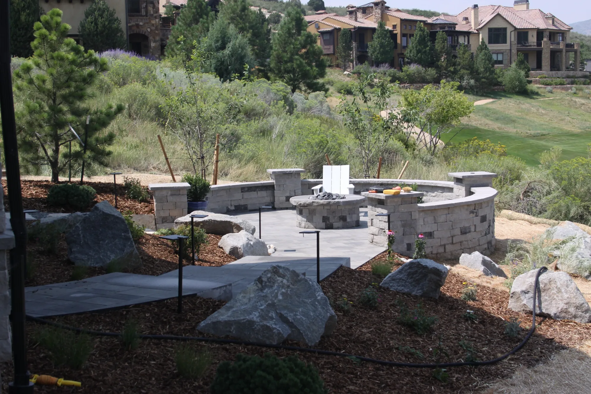 Stone fire terrace with seat walls and boulder placement on a hillside