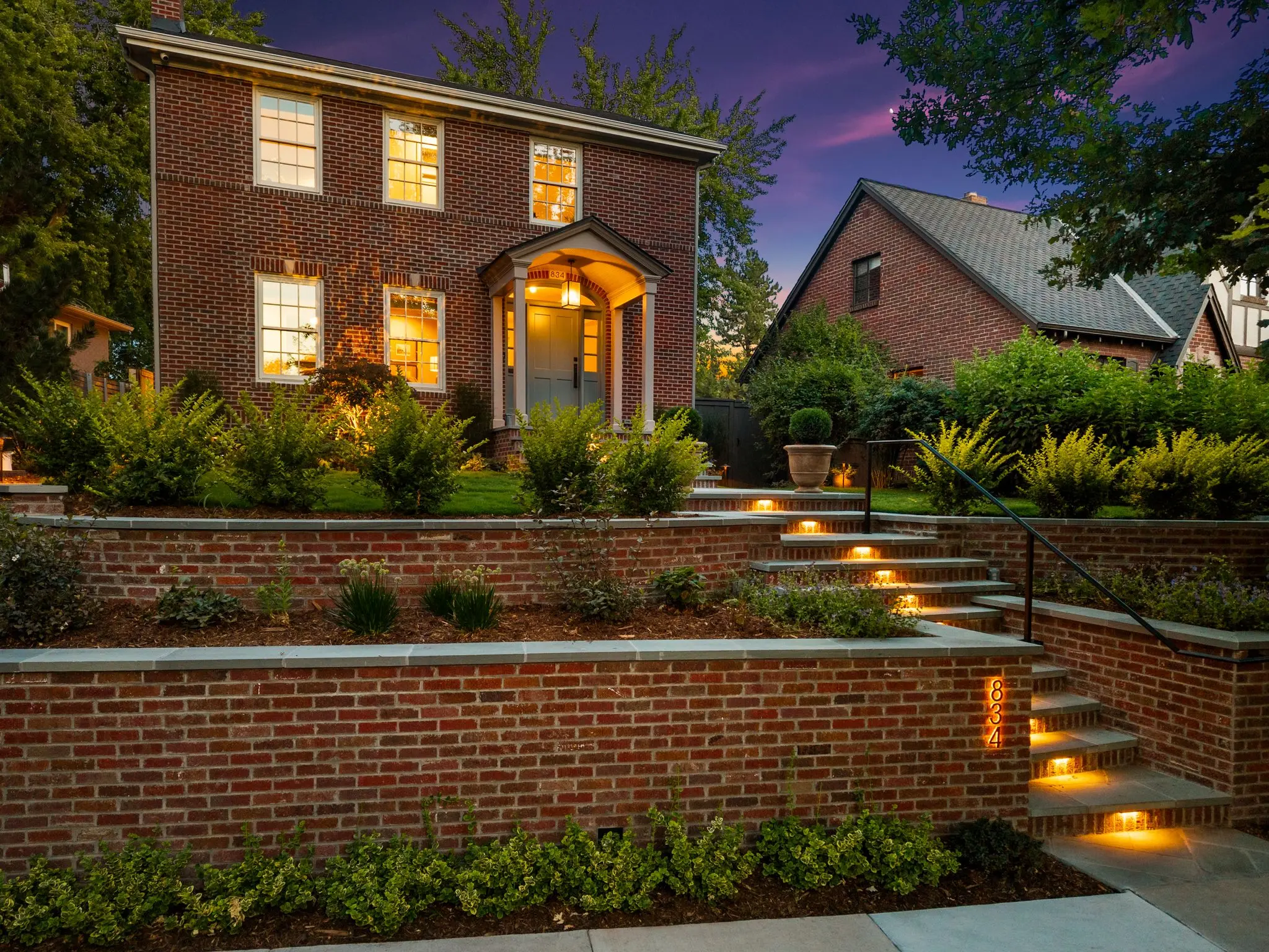 Tiered brick retaining walls with bluestone caps and integrated step lighting at twilight, Denver