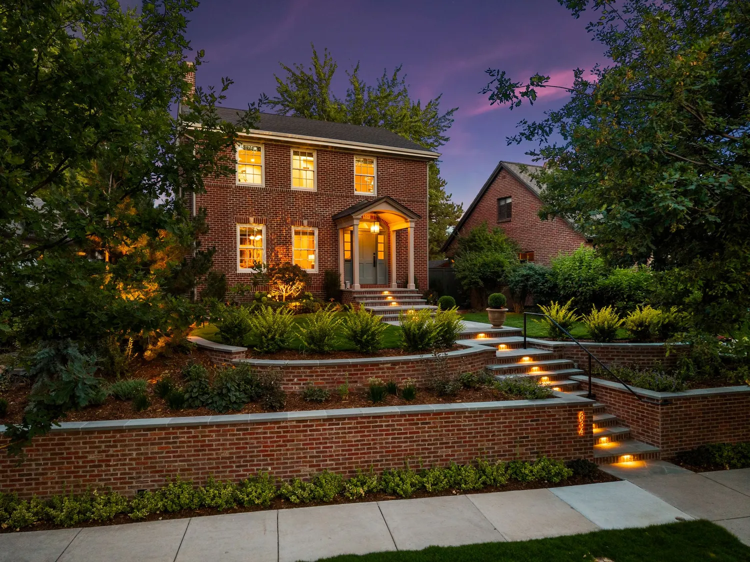 Terraced brick garden walls with lit bluestone steps at twilight