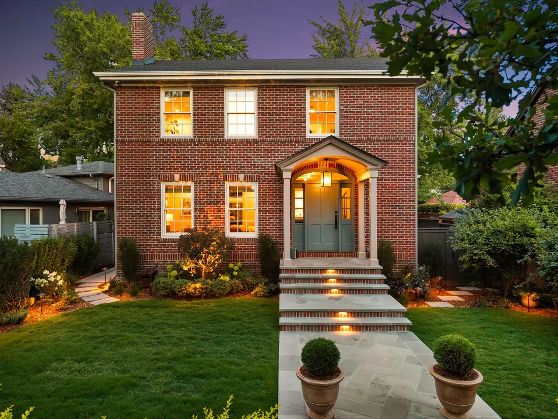 Front entry walk with clipped boxwood and warm window light