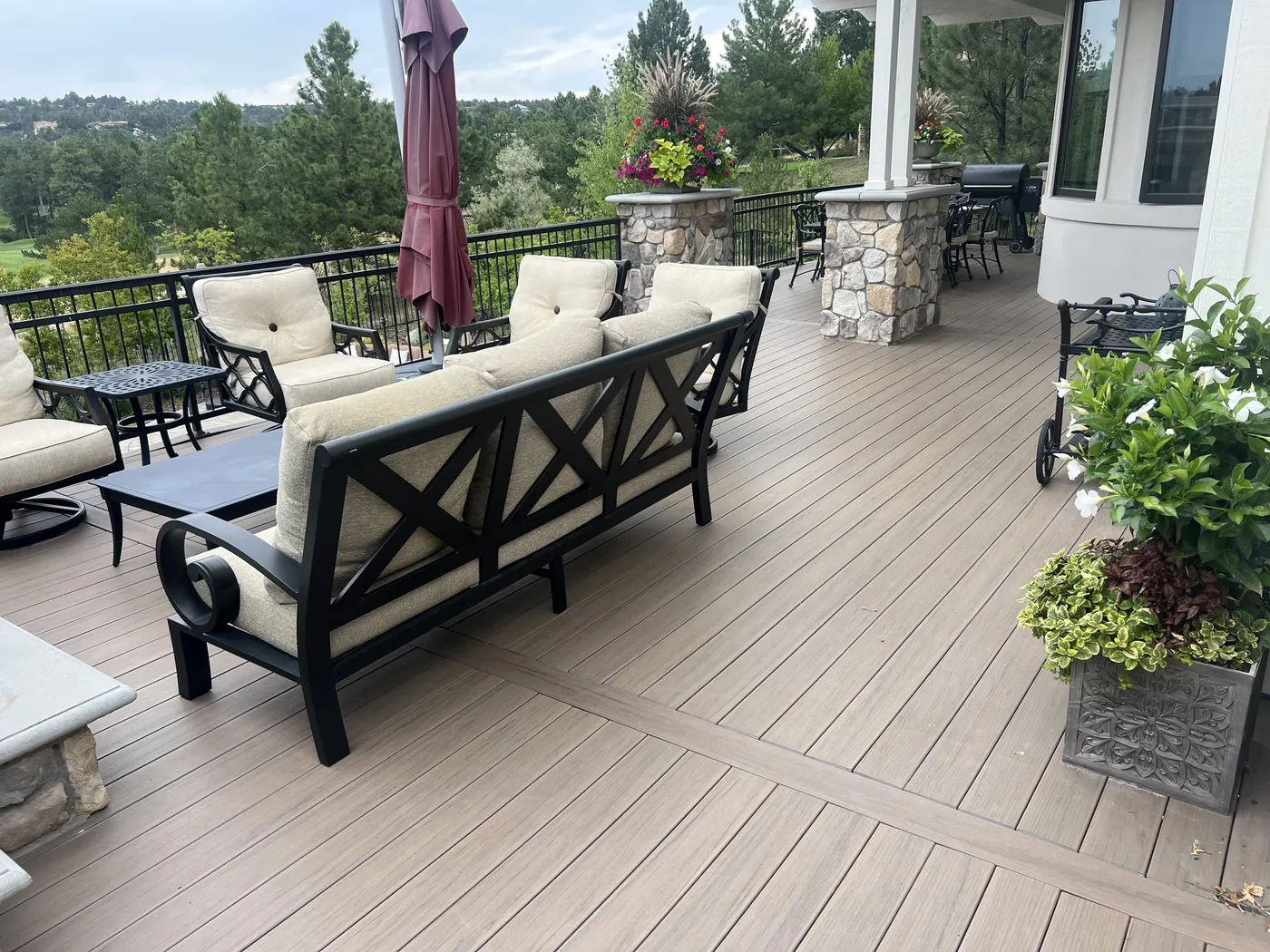 Composite deck with a contrasting border board, stone-clad columns and metal railing overlooking a golf course